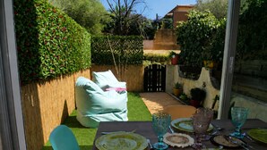 A dining area with a table set for four, surrounded by a wooden fence and greenery. - Air-conditioned studio with garden in Sanary Sur Mer (Sanary-sur-Mer)