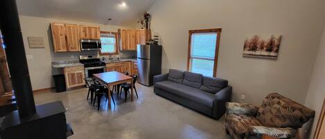 A compact kitchen with wooden cabinets, a refrigerator, and a dining area with a table and chairs.