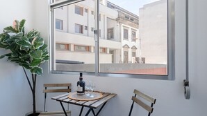 Een klein balkon met een tafel, stoelen, een fles en glazen.