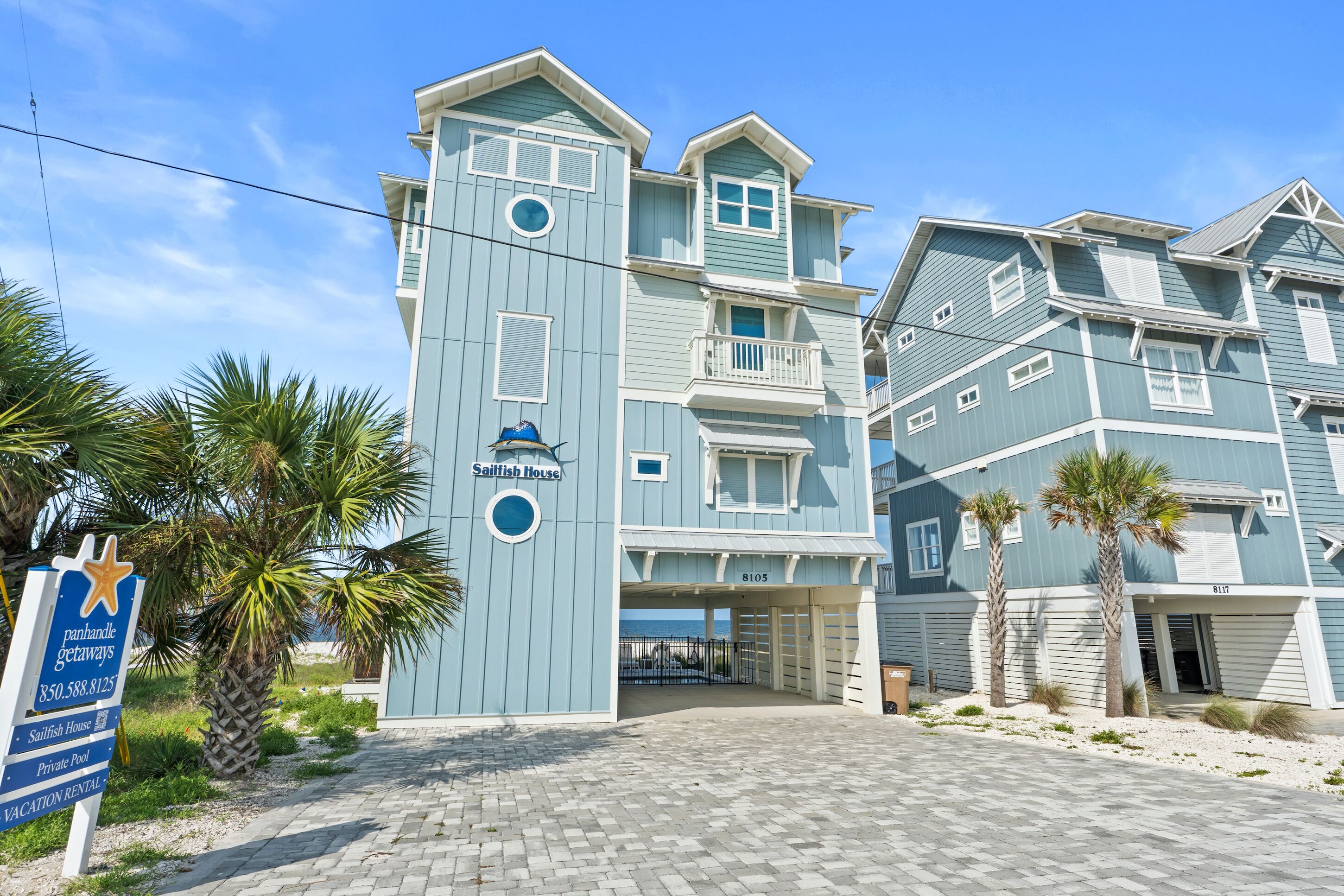 A multi-story building with a sign reading "Sailfish House" and a beach view.