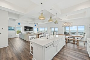 A spacious kitchen with a large island, white cabinetry, and pendant lighting. - Beach House - Sailfish by PHG (Port St. Joe)