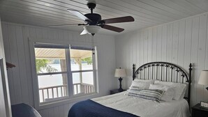 A bedroom with a bed, two bedside tables, a ceiling fan, a window with a view of the outdoors, and a chair. - Lakeside Chalet on Beautiful Gantt Lake! (Dozier)