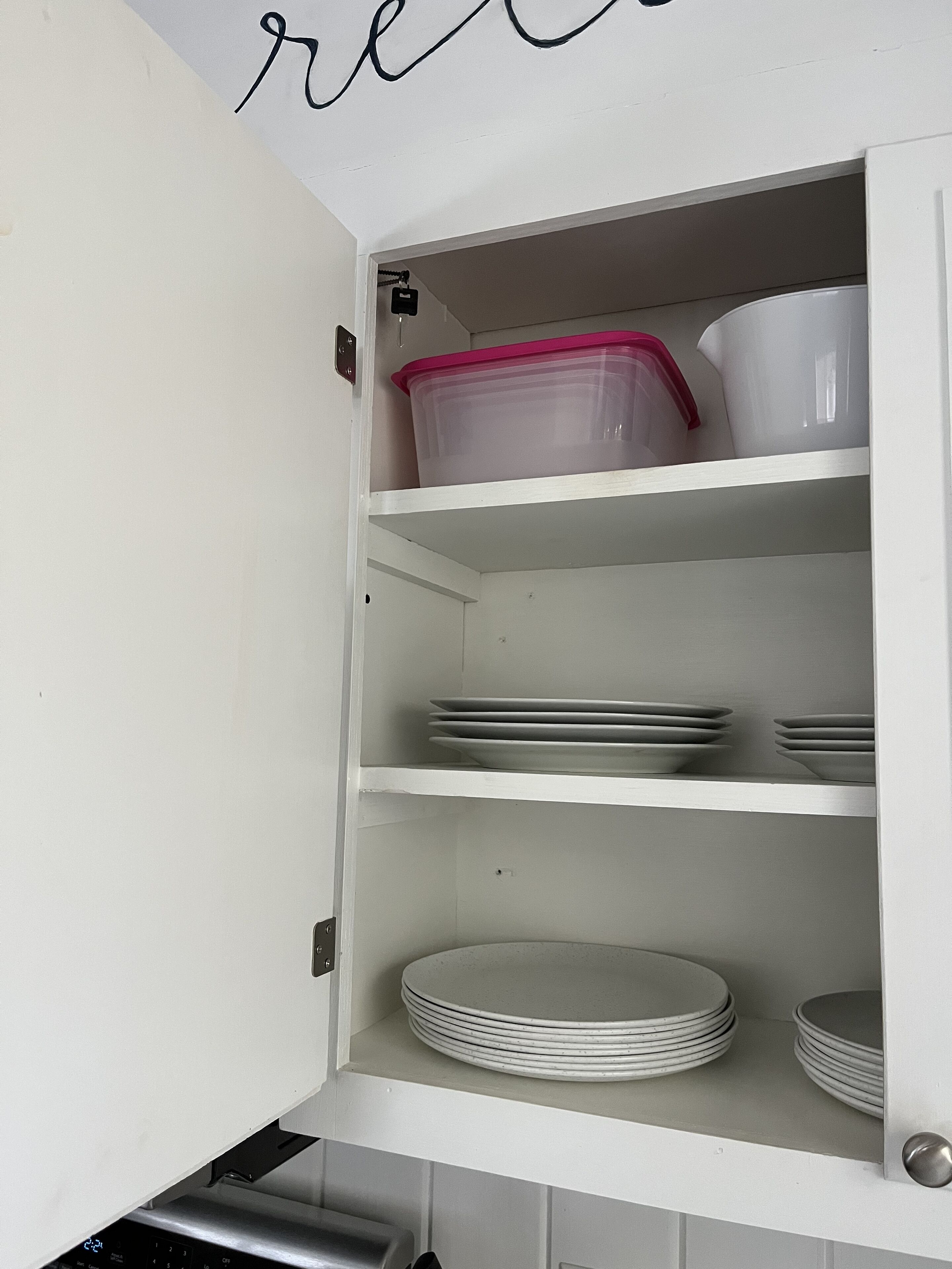 A kitchen cabinet with shelves containing plastic containers and stacked plates.