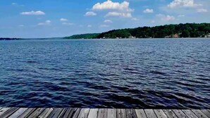 A wooden dock extending into a calm body of water with a distant shoreline covered in greenery. - Lakeside Chalet on Beautiful Gantt Lake! (Dozier)