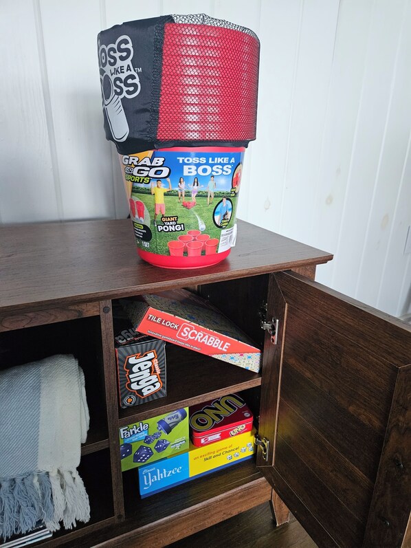 Un mueble con un recipiente grande en la parte superior y varios juegos de mesa en su interior.