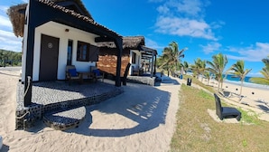 Une propriété située en bord de mer, dotée d’une structure à toit de chaume, d’un chemin piétonnier pavé et offrant une vue sur l’océan.