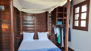 Une chambre dans un chalet en bois, avec un lit, une armoire et une fenêtre.