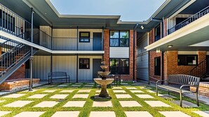A courtyard with a fountain, outdoor seating, and a multi-level building with balconies. - (12) Book Now & Save 10%! Modern July Apartment (Houston)