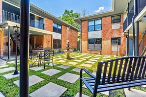 A courtyard with a checkered pattern, outdoor seating, and a fountain.
