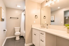 A bathroom with a toilet, sink, mirror, and a shower curtain.