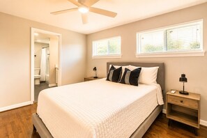 A bedroom with a bed, two bedside tables, a ceiling fan, and a window.