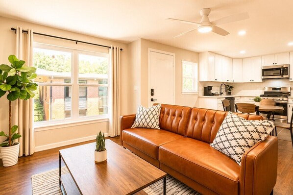 A living room with a brown leather sofa, a coffee table, and a potted plant.