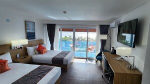 Ein Hotelzimmer mit zwei Betten, einem Schreibtisch, einem Fernseher und einem Balkon mit Blick.