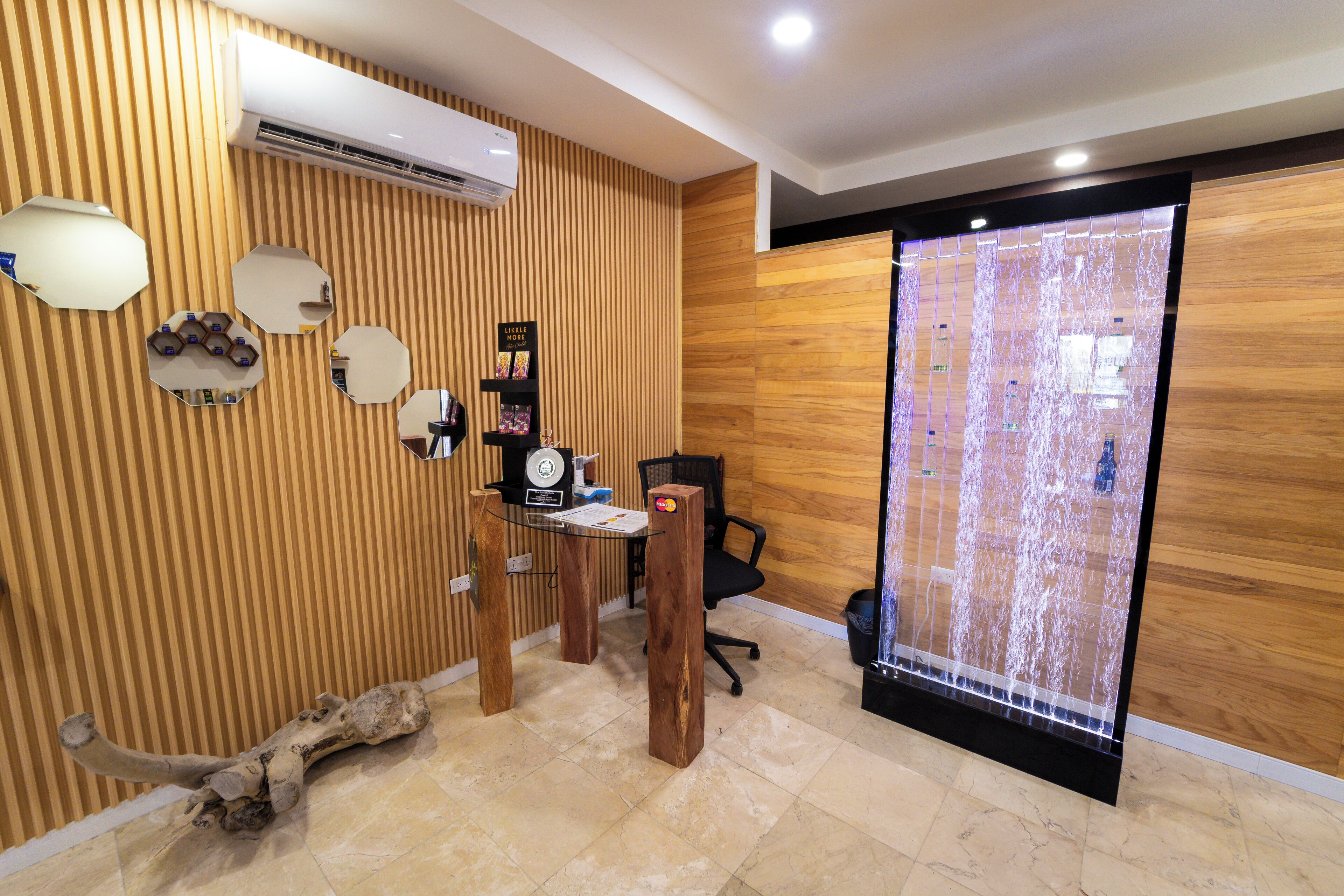 A modern reception area with a wooden panel wall, a reception desk, a black office chair, and a decorative water feature.