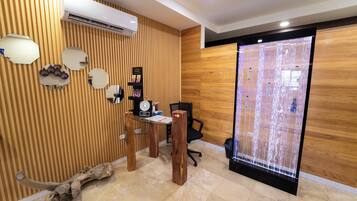 A modern reception area with a wooden panel wall, a reception desk, a black office chair, and a decorative water feature.