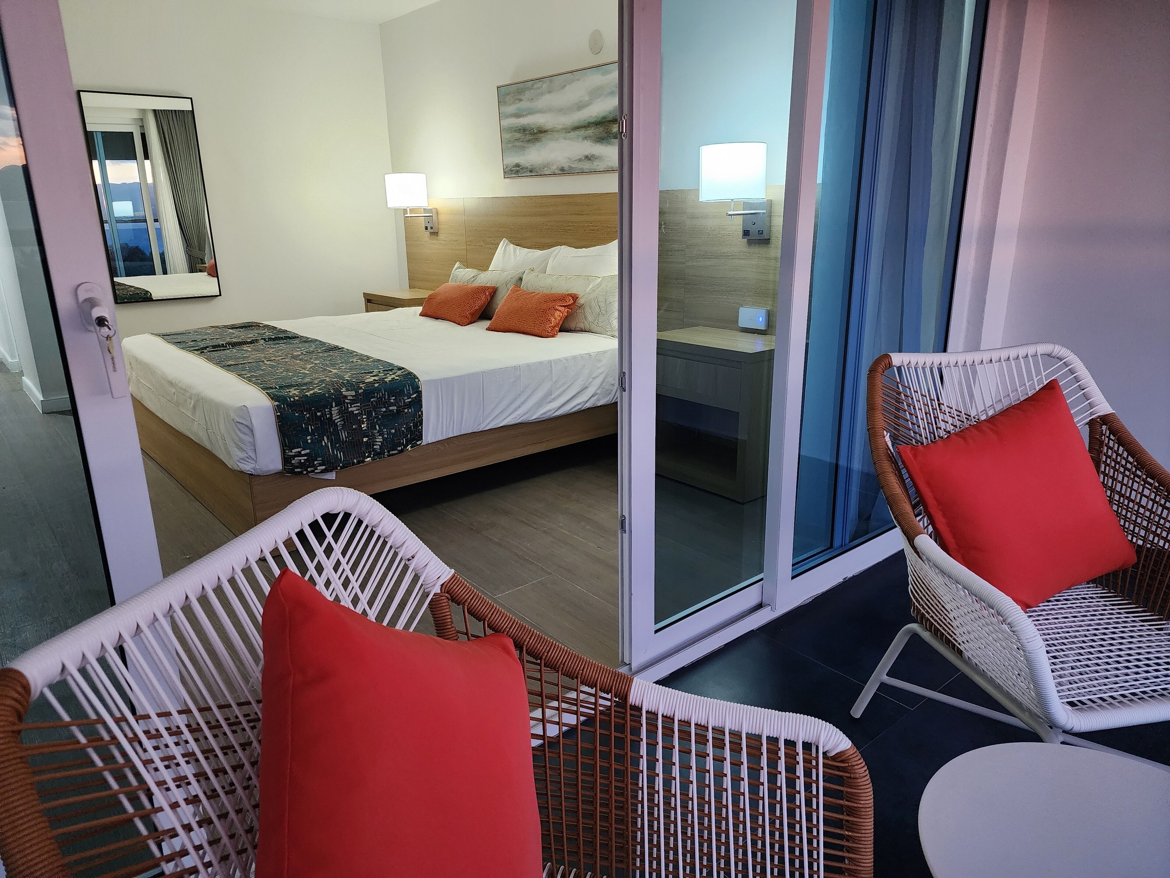 Una habitación de hotel con una cama, una mesita de noche, una lámpara y una silla.