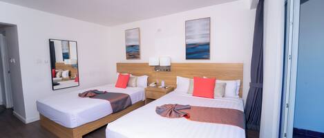 Une chambre d’hôtel avec deux lits, une tête de lit en bois, une table de chevet avec un téléphone et une fenêtre avec des rideaux.