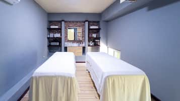 Two single beds with white linens, a dresser, and a large mirror.