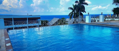 Una piscina al aire libre, sombrillas, tumbonas