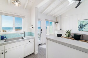A bright kitchen with a view of the ocean, white cabinetry, and a large island.