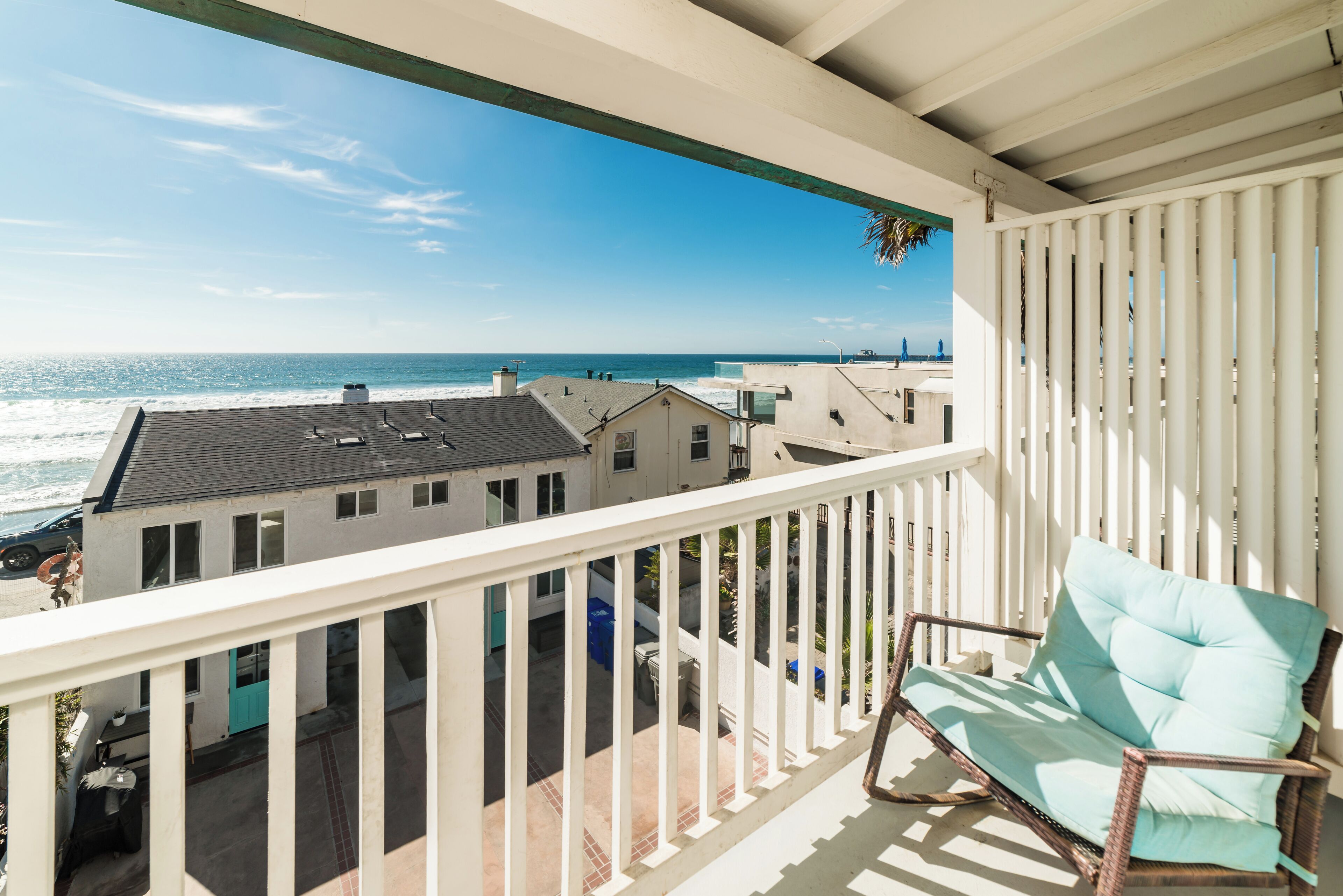 A balcony with a view of the ocean and neighboring buildings.