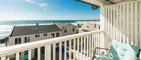 A balcony with a view of the ocean and neighboring buildings.