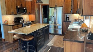A modern kitchen with wooden cabinets, stainless steel appliances, and a granite countertop. - Private MNT Escape close to DuPont, Pisgah Forest, Brevard, Hendersonville. (Hendersonville)