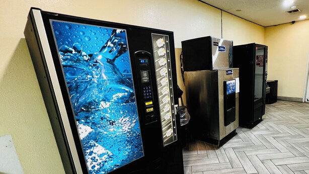 Una hilera de dispensadores automáticos de bebidas con pantalla digital y panel de control.