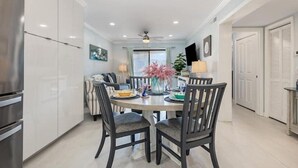 A modern kitchen with a dining area, featuring a round table with chairs, a refrigerator, and a ceiling fan. - The Sea Cabin w/ Partial Ocean View & Pool, Golf, Beach (North Myrtle Beach)