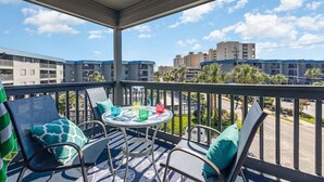 A balcony with a round table and chairs, a view of buildings, and a clear sky. - The Sea Cabin w/ Partial Ocean View & Pool, Golf, Beach (North Myrtle Beach)