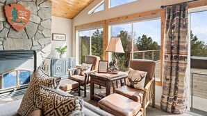 A cozy living room with leather furniture, a stone wall, and a fireplace. - Mountain Retreat on 5 acres with nature views, deck, hot tub, EV charging (Mariposa)