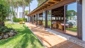 A covered outdoor seating area with tables and chairs, a tiled patio, and a view of the surrounding greenery and buildings. - Fantastic 1 bed townhouse close to Marbella (Marbella)