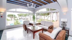 A spacious room with a large glass wall, a wooden ceiling, and a central seating area with a glass coffee table. - Fantastic 1 bed townhouse close to Marbella (Marbella)