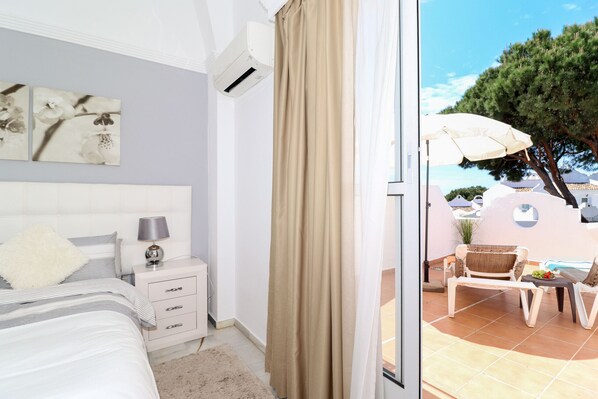 A bedroom with a bed, bedside table, lamp, and air conditioning unit. - Fantastic 1 bed townhouse close to Marbella (Marbella)