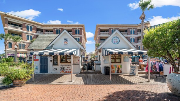 A boardwalk with shops and a sign for 'Charles' Donuts. - 30A Beach House - Beach Bikin (Panama City Beach)