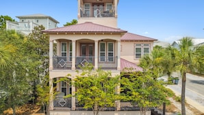 A two-story house with a balcony, large windows, and a red roof. - 30A Beach House - Beach Bikin (Panama City Beach)