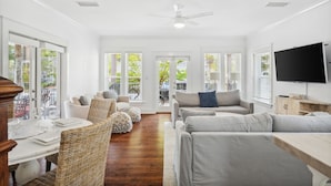 A spacious living room with a wooden dining table, wicker chairs, and a grey sofa. - 30A Beach House - Beach Bikin (Panama City Beach)