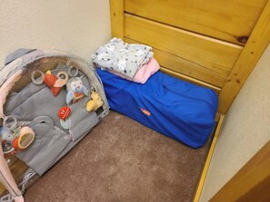 A child's play area with a small bed, a storage bin with toys, and a blue blanket on the floor. - Wildlife Ridge-Views, Gameroom, Hot Tub 4300' Elev (Mars Hill)
