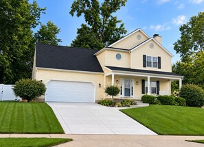 A two-story house with a garage, a front porch, and a well-maintained lawn. - ☘️ 10 mins to Notre Dame, 4 Bedrooms, Garage Park, Restaurants Close. Go Irish!☘️ (South Bend)