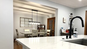 A modern kitchen with a white marble countertop, a black faucet, and a wooden door. - ☘️ 10 mins to Notre Dame, 4 Bedrooms, Garage Park, Restaurants Close. Go Irish!☘️ (South Bend)