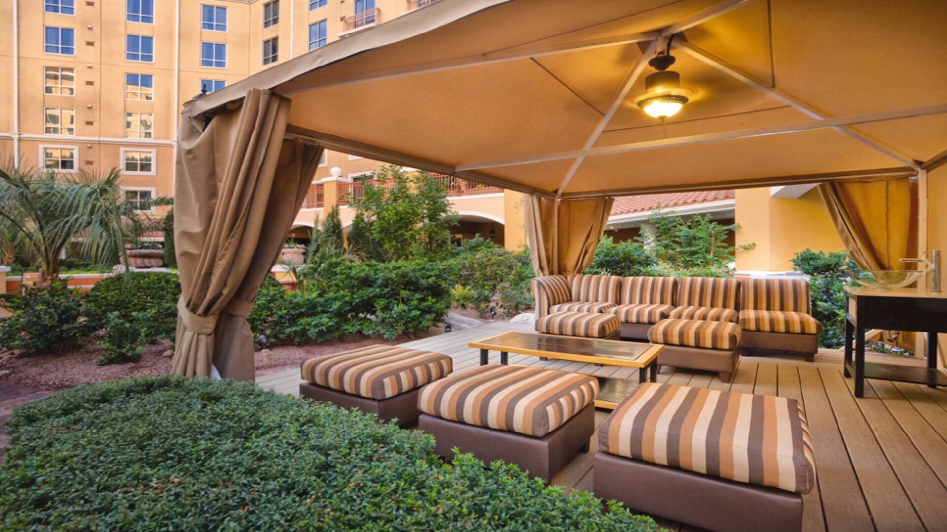 An outdoor patio area with a sofa set, ottomans, and a table under a canopy.