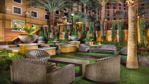 An outdoor lounge area with sofas and planters, surrounded by palm trees and greenery. - 3BD/Vegas - Full Kitchen, Private Living Room, Pools and Hot Tubs! (Las Vegas)