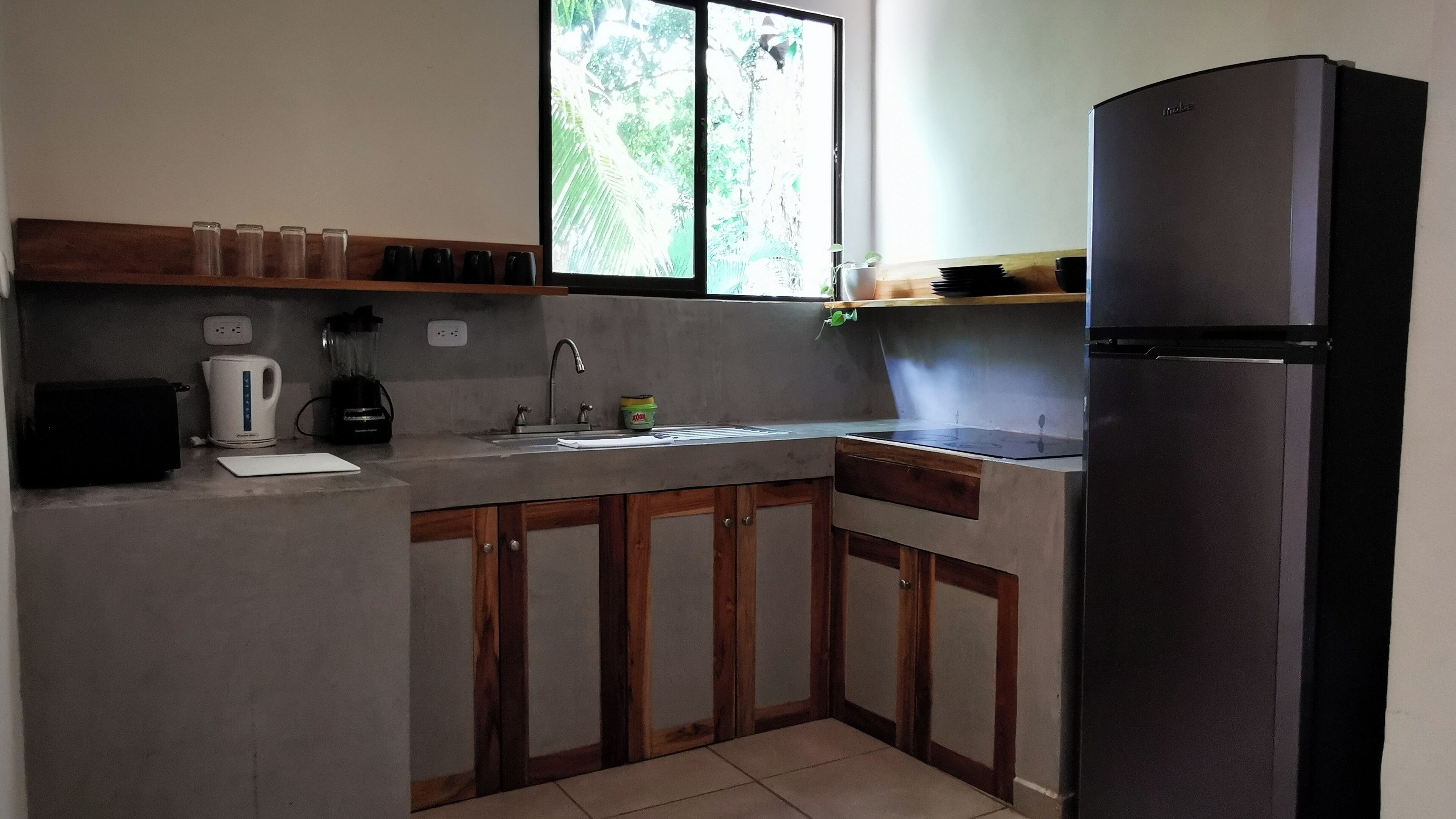 A compact kitchen with a sink, a stove, a refrigerator, and wooden cabinets.