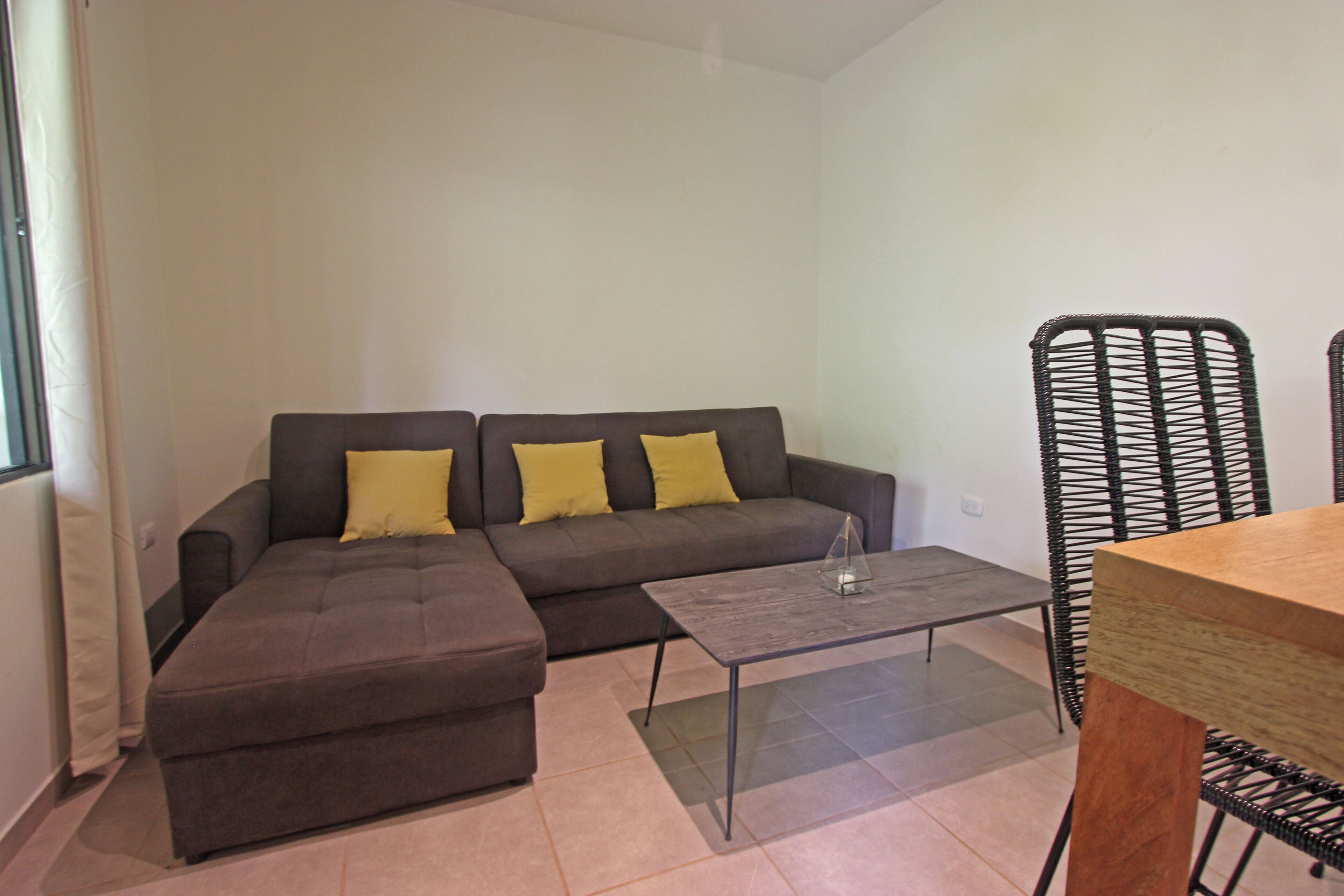 Ein modernes Wohnzimmer mit einer Couch, einem Hocker und einem kleinen Tisch.