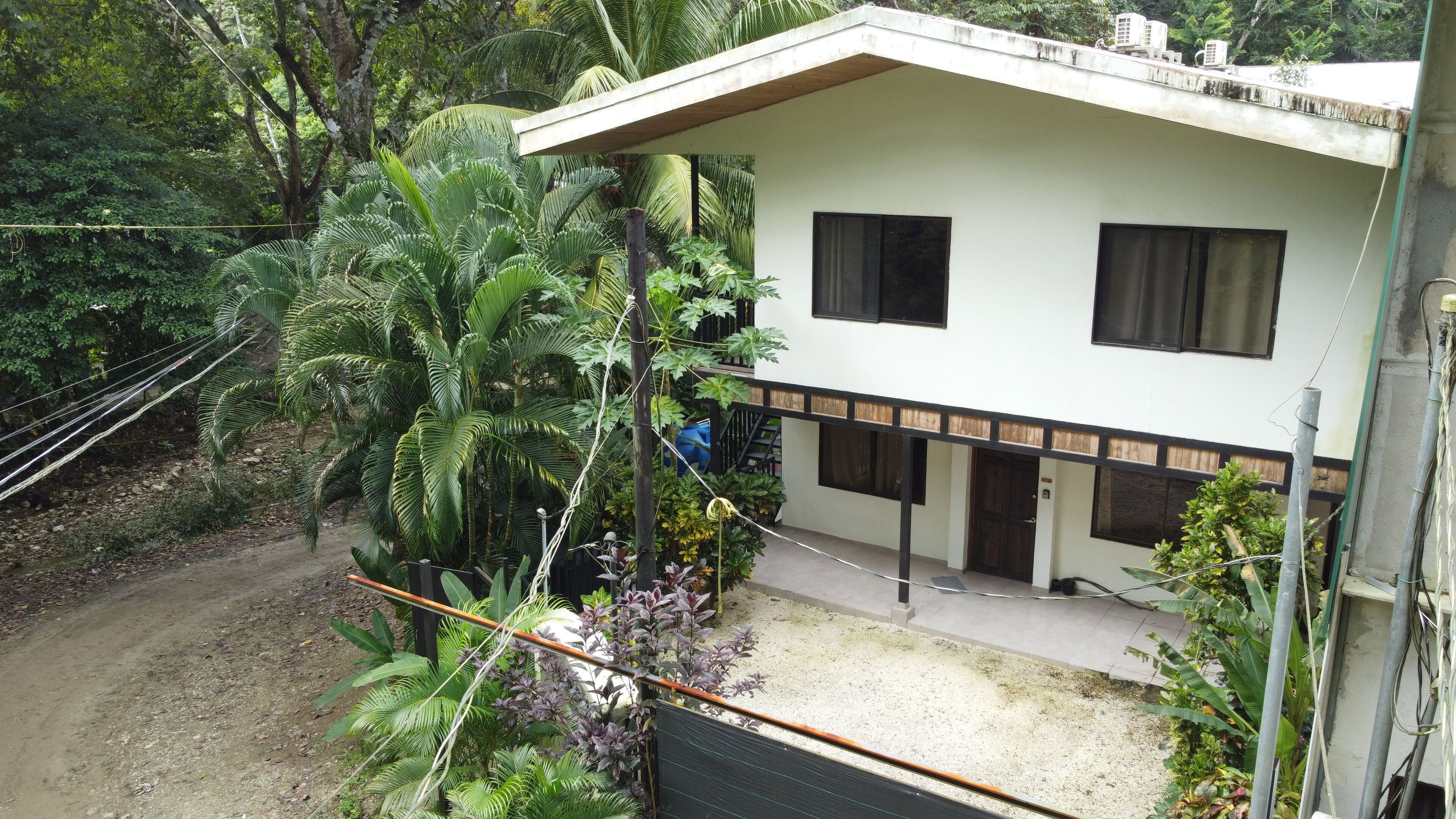 A two-story building with a white exterior and dark window frames. There is a visible staircase leading to the upper floor.