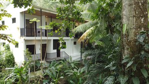 A two-story building with balconies surrounded by dense tropical vegetation.