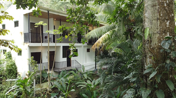 A two-story building with balconies surrounded by dense tropical vegetation.