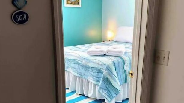 A bedroom with a bed, a ceiling fan, and a striped rug. - Cozy ranch, minutes from both historic downtown Savannah and Tybee Beaches. (Savannah)