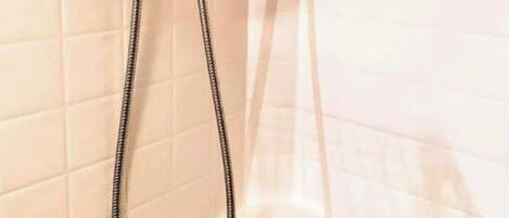A shower with a handheld hose and a wall-mounted showerhead.