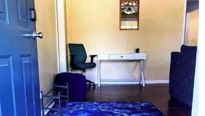 A hallway with a blue patterned carpet, a desk with a chair, and a door. - Cozy ranch, minutes from both historic downtown Savannah and Tybee Beaches. (Savannah)